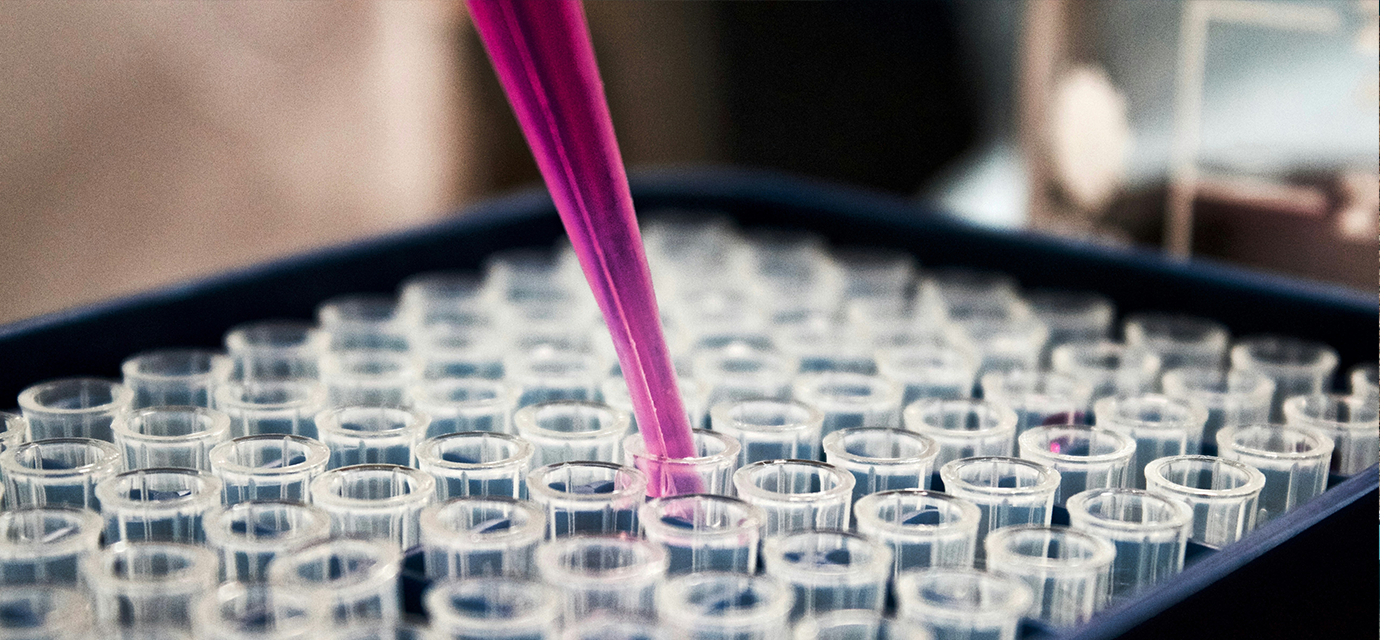 a box full of test tubes seen from an isometric perspective with a dropped full of pink liquid above them.